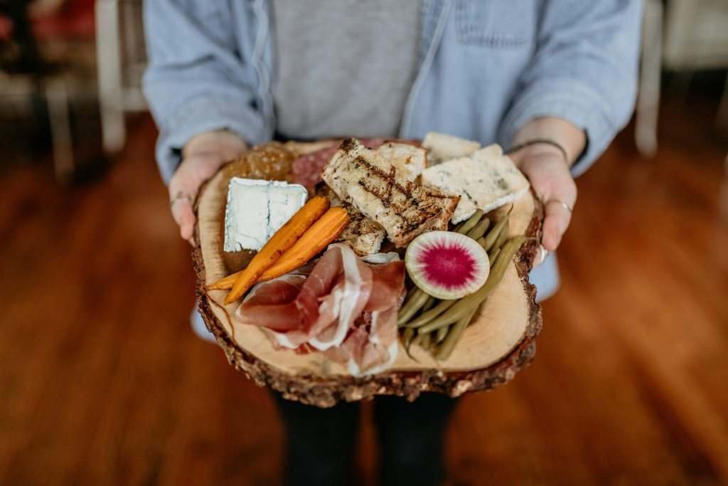 a person holding a platter of meats and cheeses