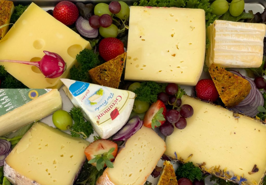 a variety of cheeses and fruits are arranged in a tray